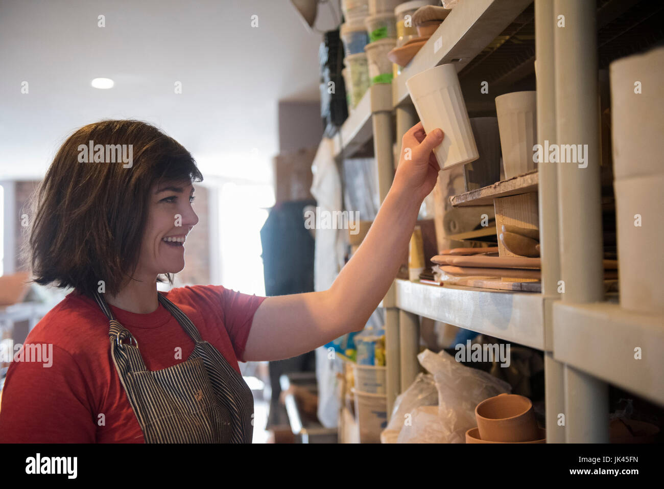 Lächelnde Frau kaukasischen Regal im Workshop Tasse Inverkehrbringen Stockfoto