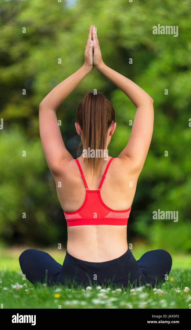 Rückansicht des jungen Fit gesunde Frau Frauen oder Mädchen üben Yoga-Pose auf einer Matte außerhalb in einer ruhigen grünen Natur Stockfoto