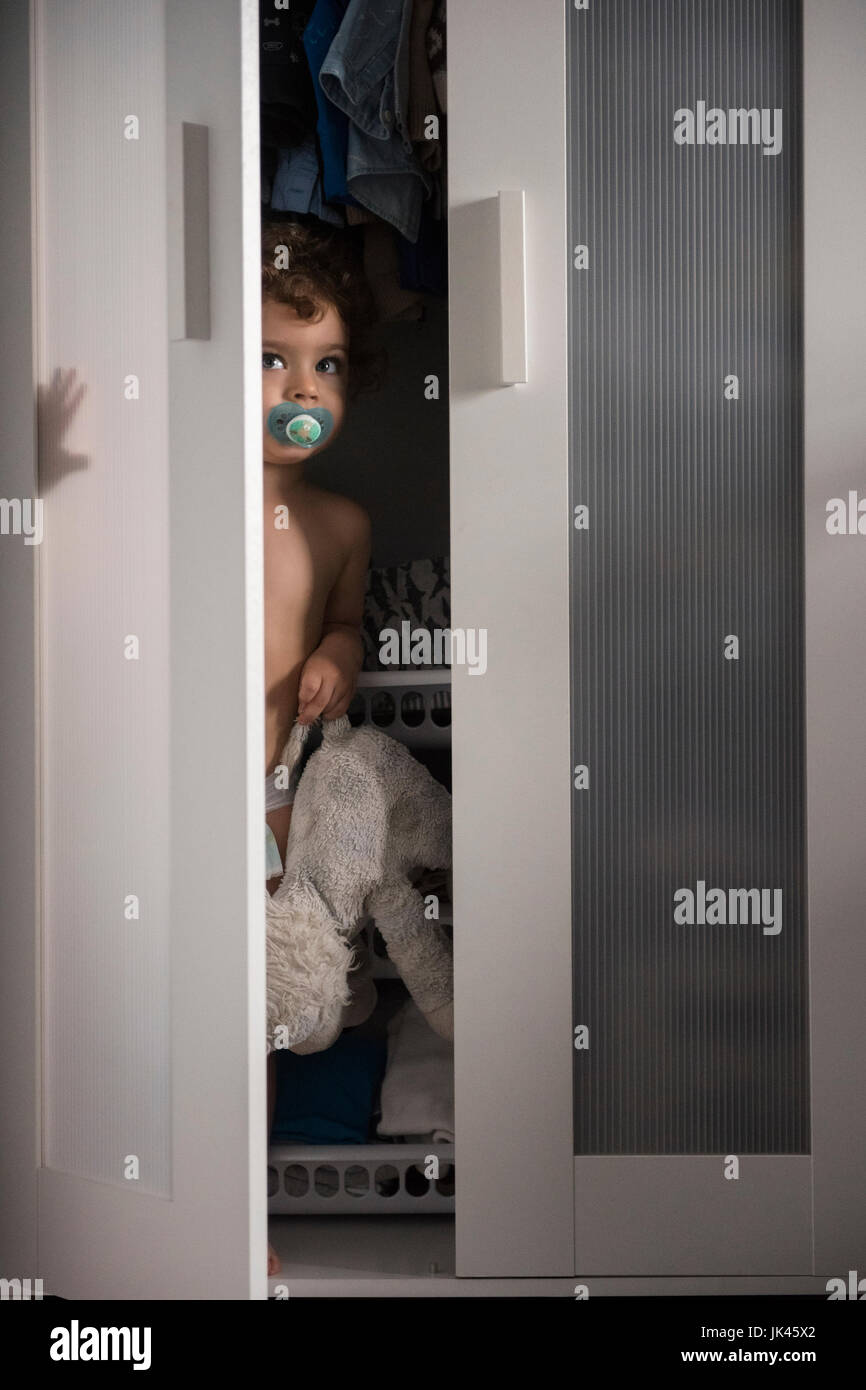 Kaukasische junge versteckt sich im Schrank spähen aus Tür Stockfoto