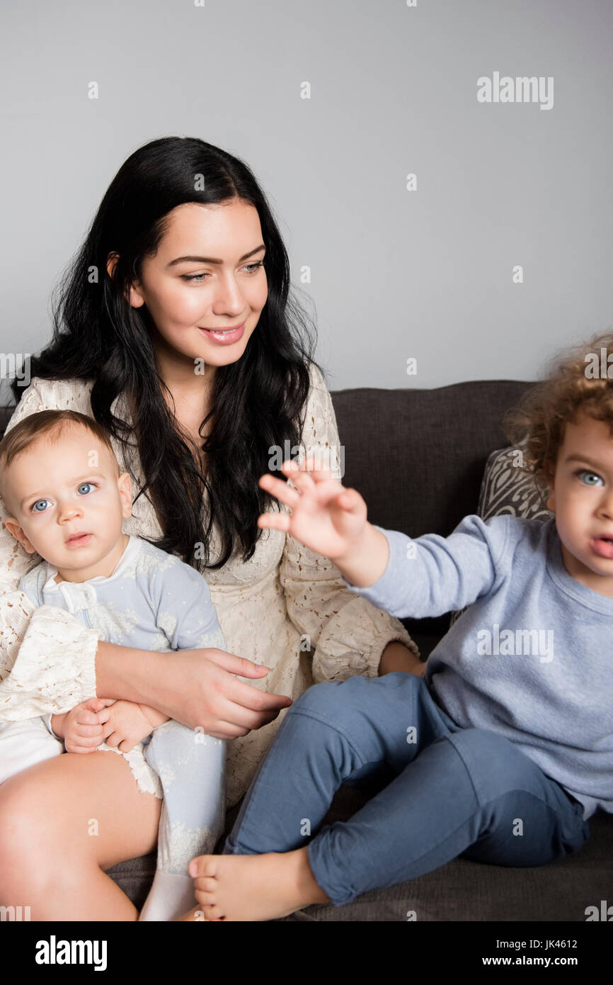 Kaukasische Mutter mit Söhnen auf Sofa sitzen Stockfoto