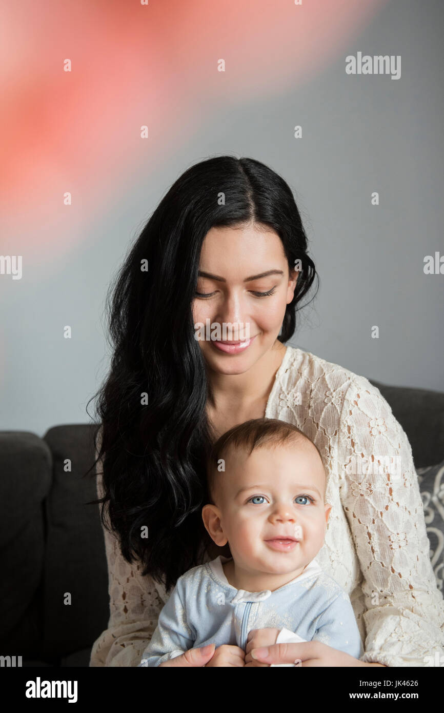 Kaukasische Mutter Holding lächelndes Baby Sohn im Schoß Stockfoto