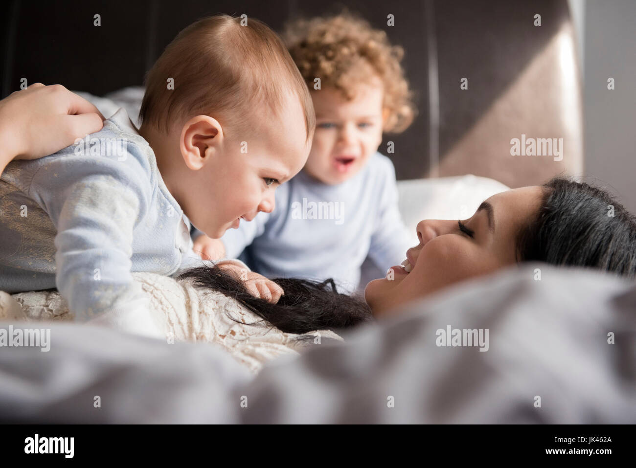 Kaukasische Mutter auf Bett spielen mit Söhnen Stockfoto