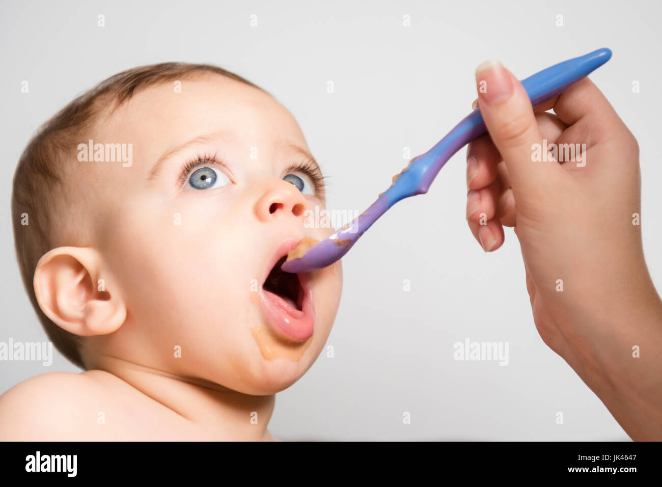 Hand des kaukasischen Mutter Fütterung Baby Sohn mit Löffel Stockfoto