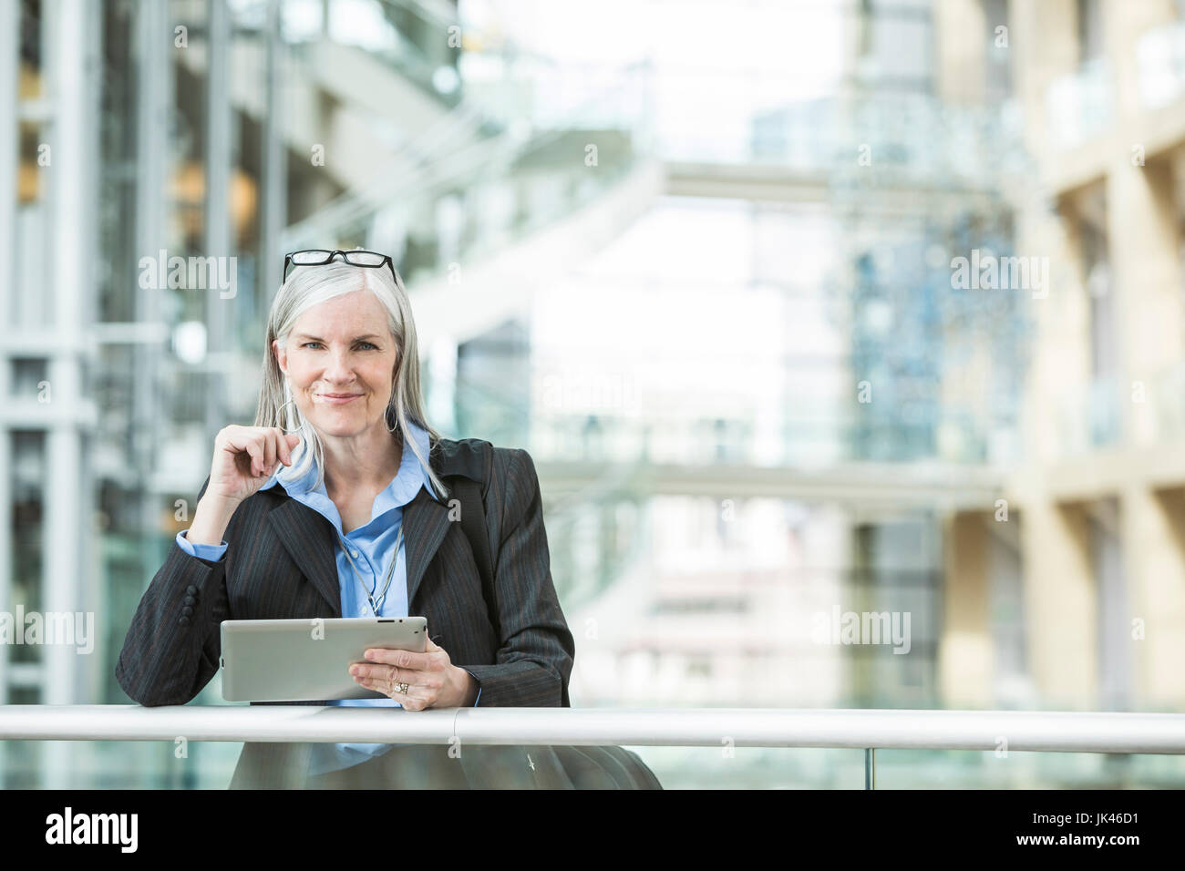Kaukasische Geschäftsfrau stützte sich auf Geländer in Lobby mit digital-Tablette Stockfoto
