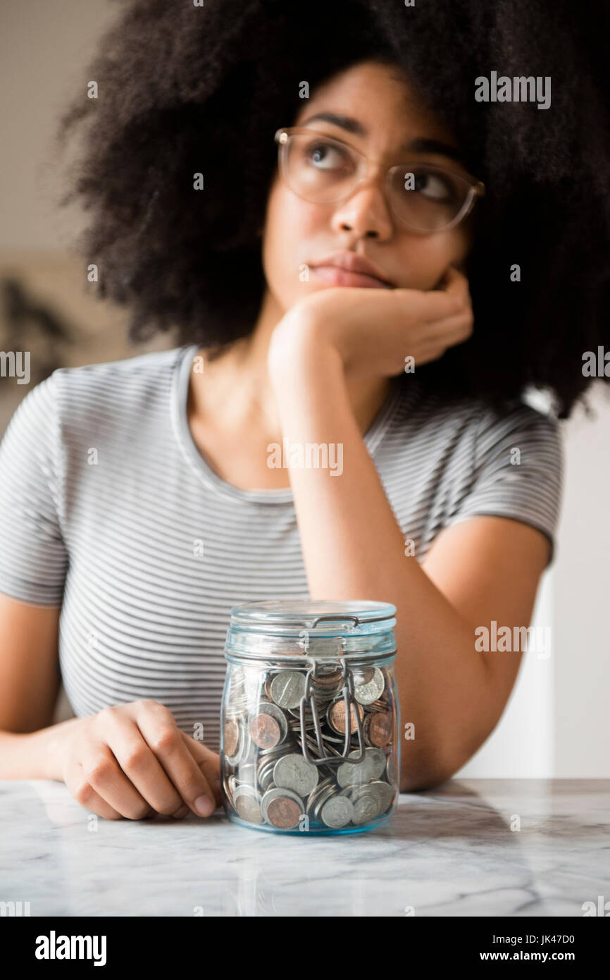 Nachdenklich afroamerikanische Frau mit Glas voller Münzen Stockfoto