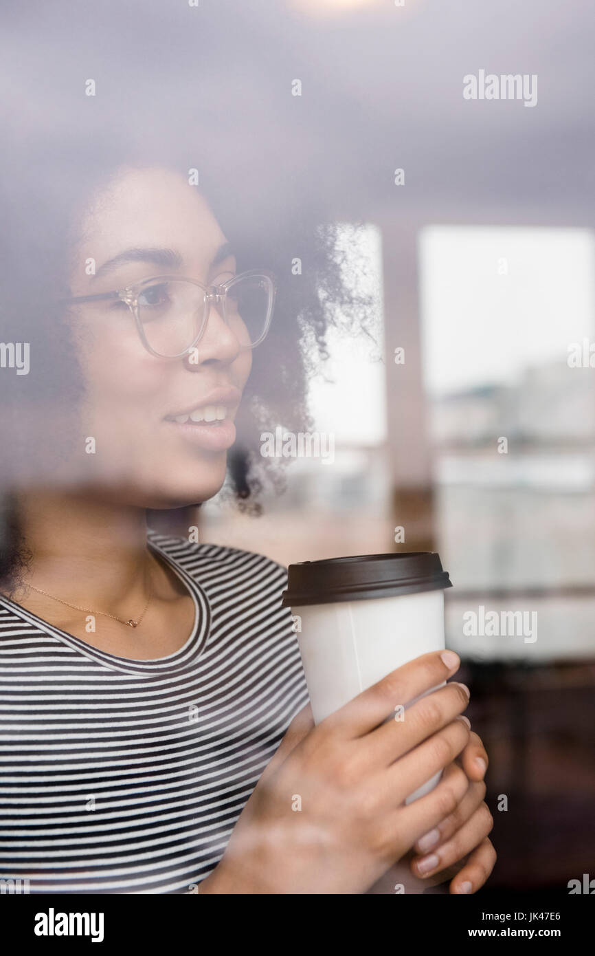 Nachdenklich Afroamerikanerfrau Kaffeetrinken hinter Fenster Stockfoto