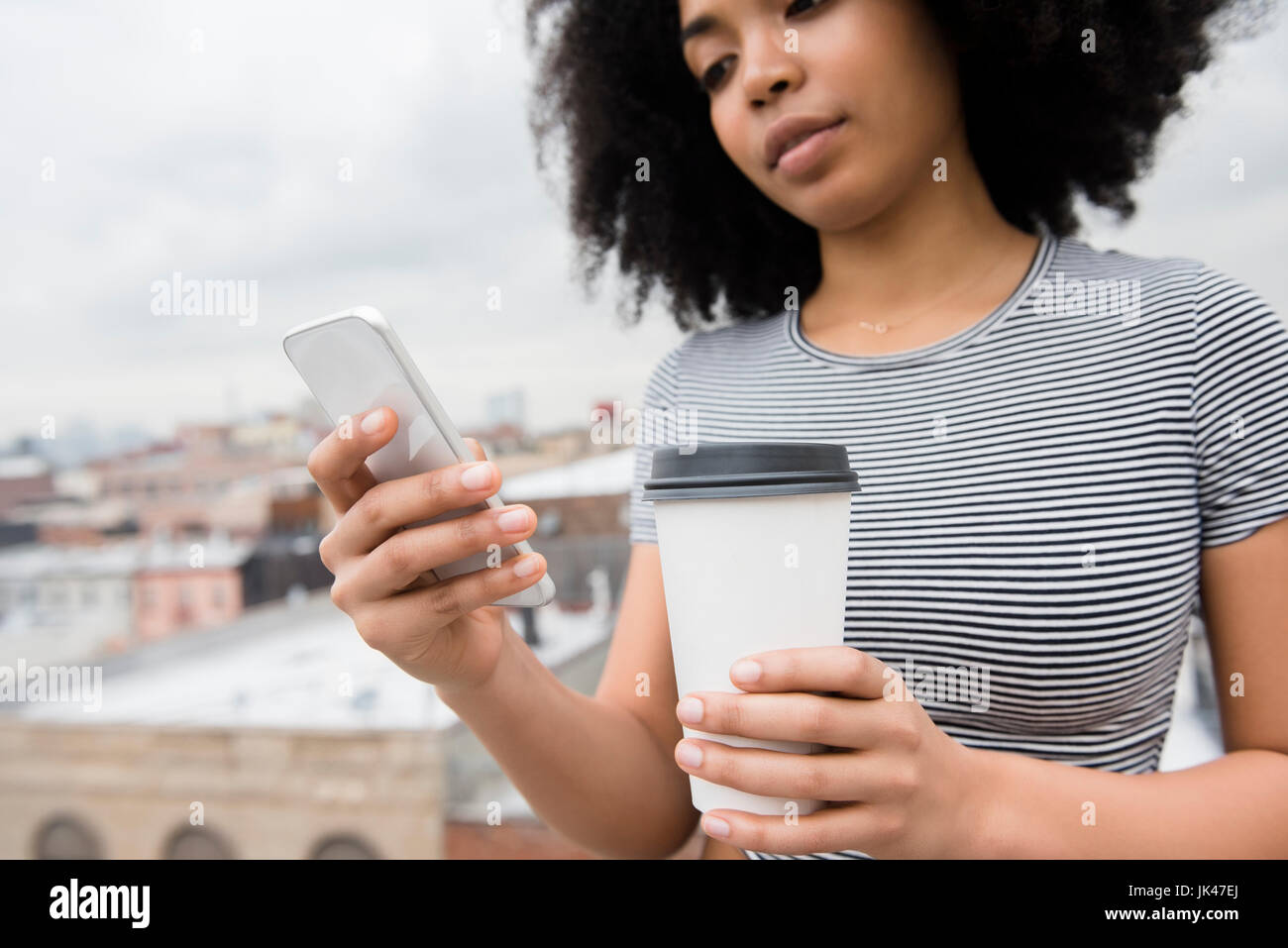 Afroamerikanische Frau, trinken Kaffee und SMS auf dem Handy Stockfoto
