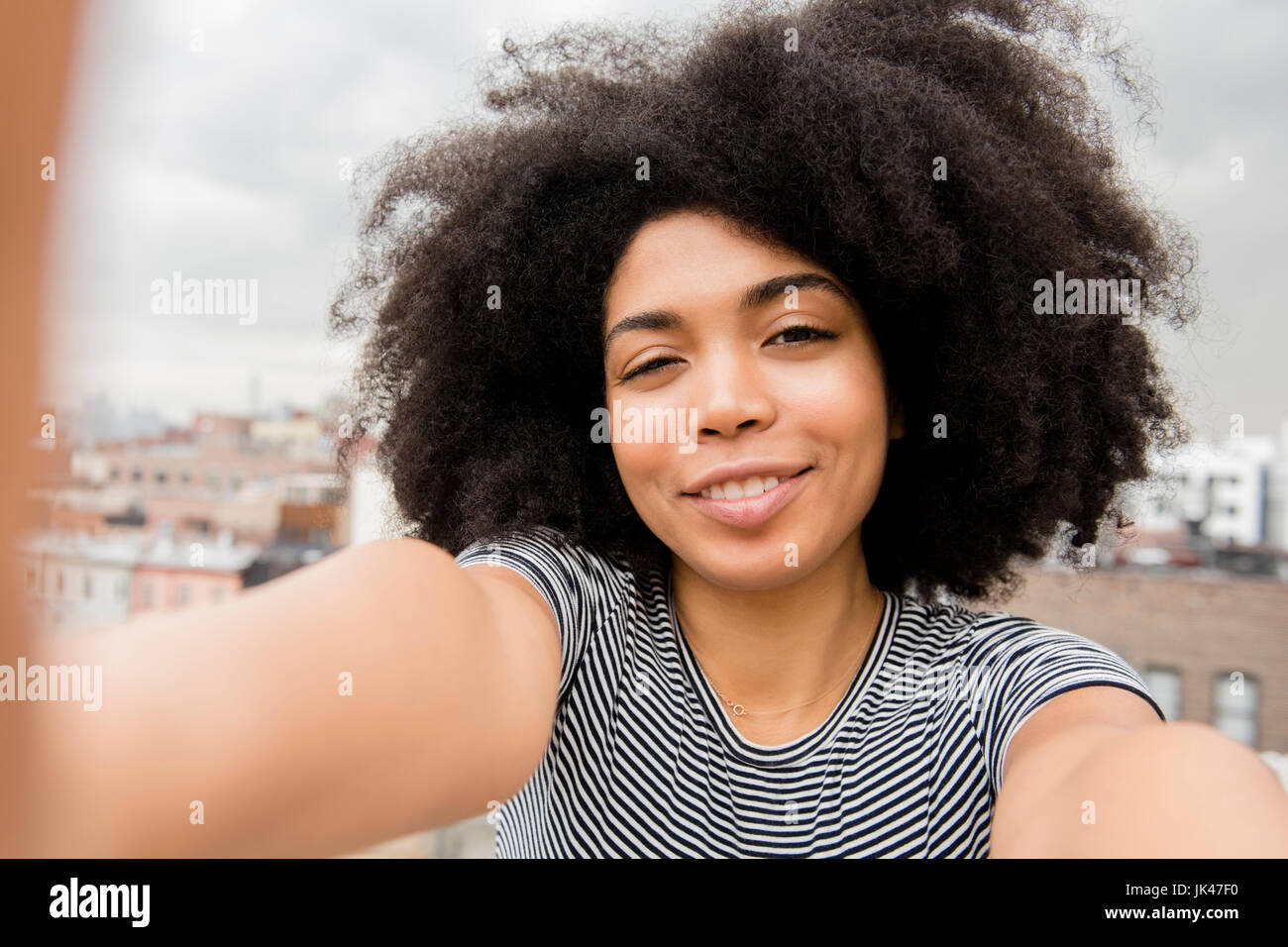 Lächelnde afroamerikanische Frau posiert für Selfie auf Dach Stockfoto
