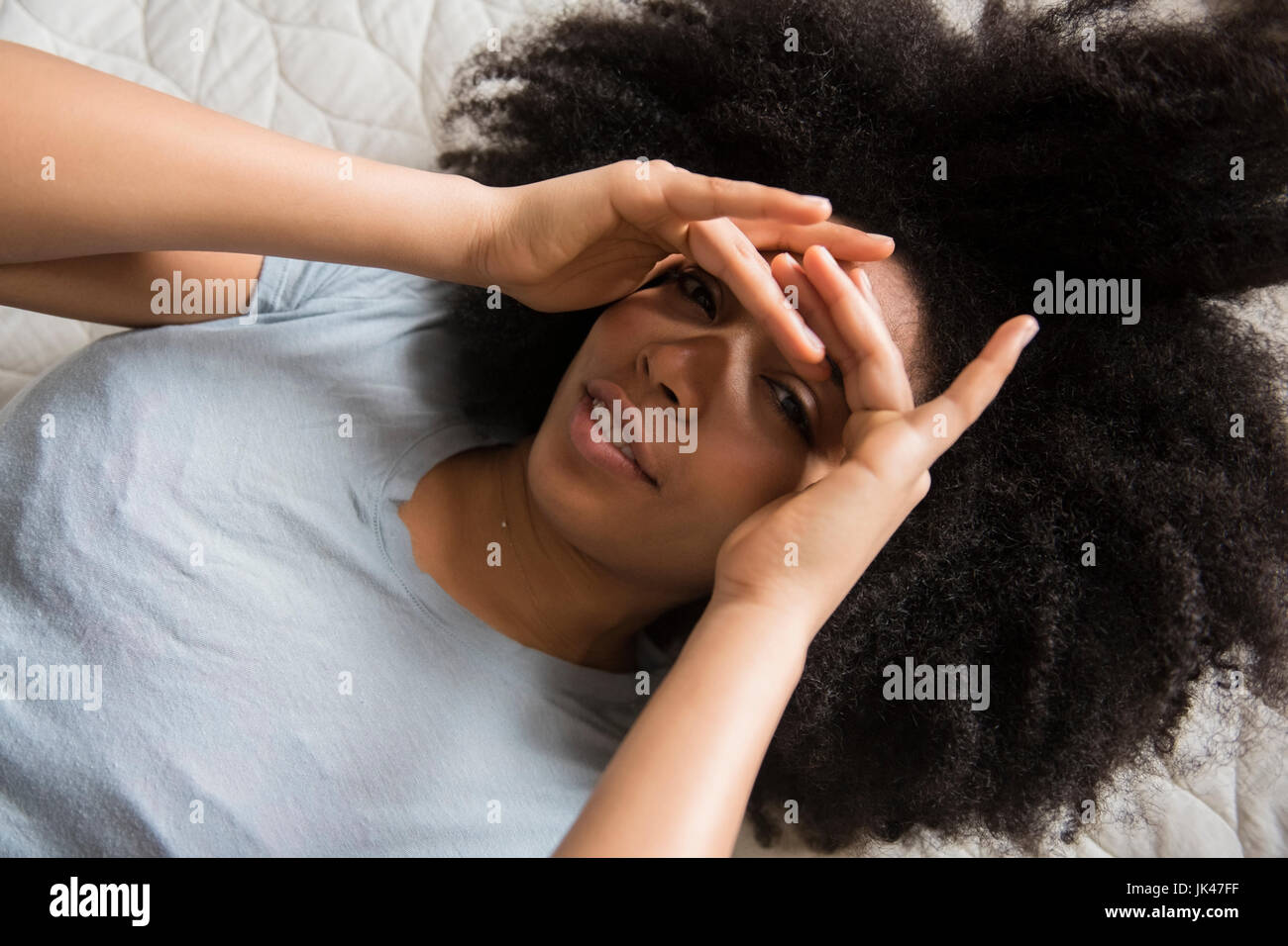 Afroamerikanische Frau im Bett Abschirmung Augen Stockfoto
