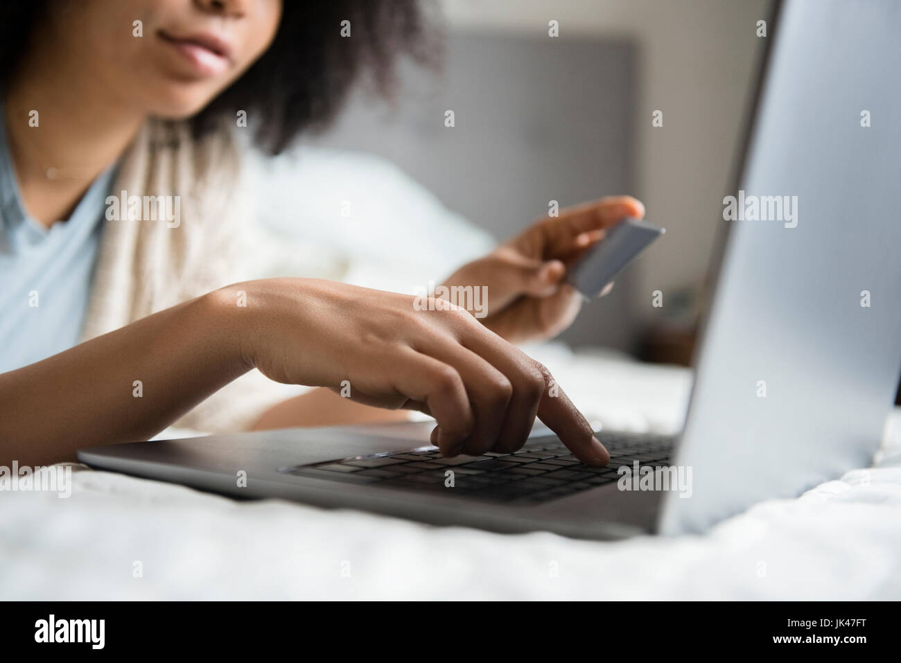 Afroamerikanische Frau im Bett mit Laptop Online-shopping Stockfoto