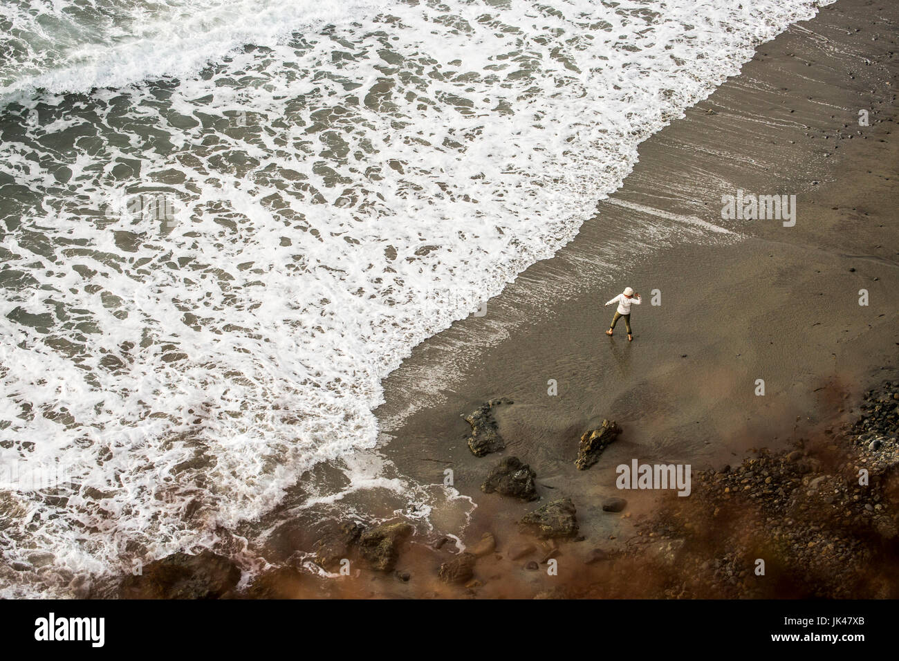Fernen kaukasischen Frau wirft Stein am Ocean beach Stockfoto