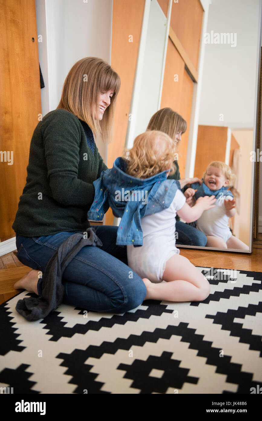 Reflexion im Spiegel der kaukasischen Mutter und Tochter am Boden kniend Stockfoto