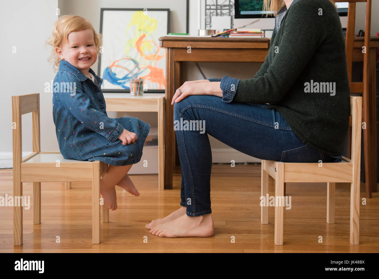 Kaukasische Mutter und Tochter sitzen auf kleinen Stühlen im home-office Stockfoto