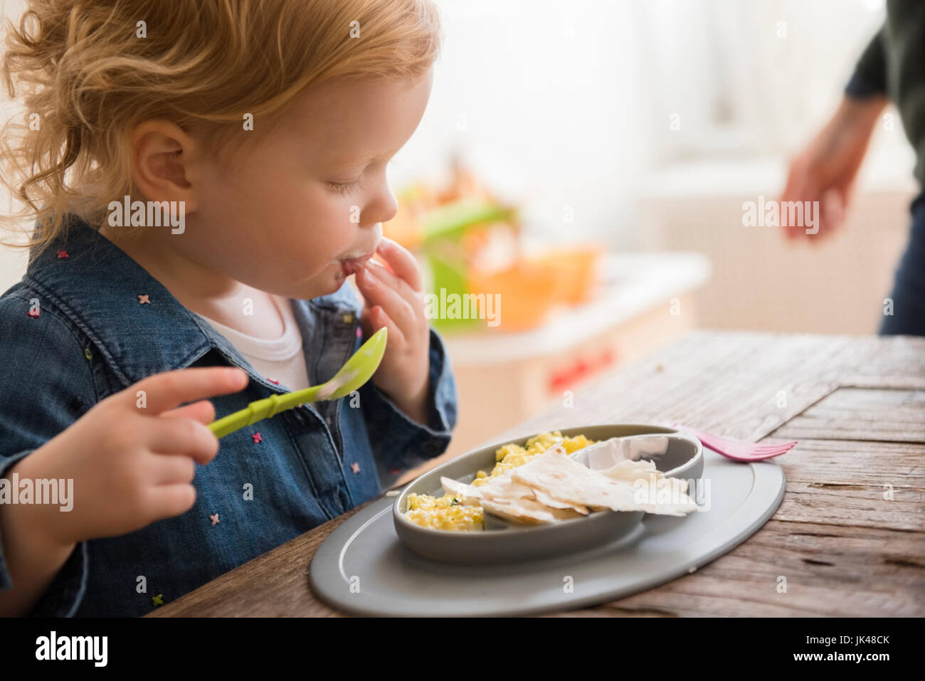 Kaukasische Mädchen Essen mit den Fingern und Löffel Stockfoto