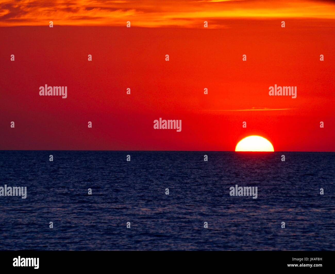 Orangefarbenen Himmel und indigo Wasser bei Sonnenuntergang Stockfoto
