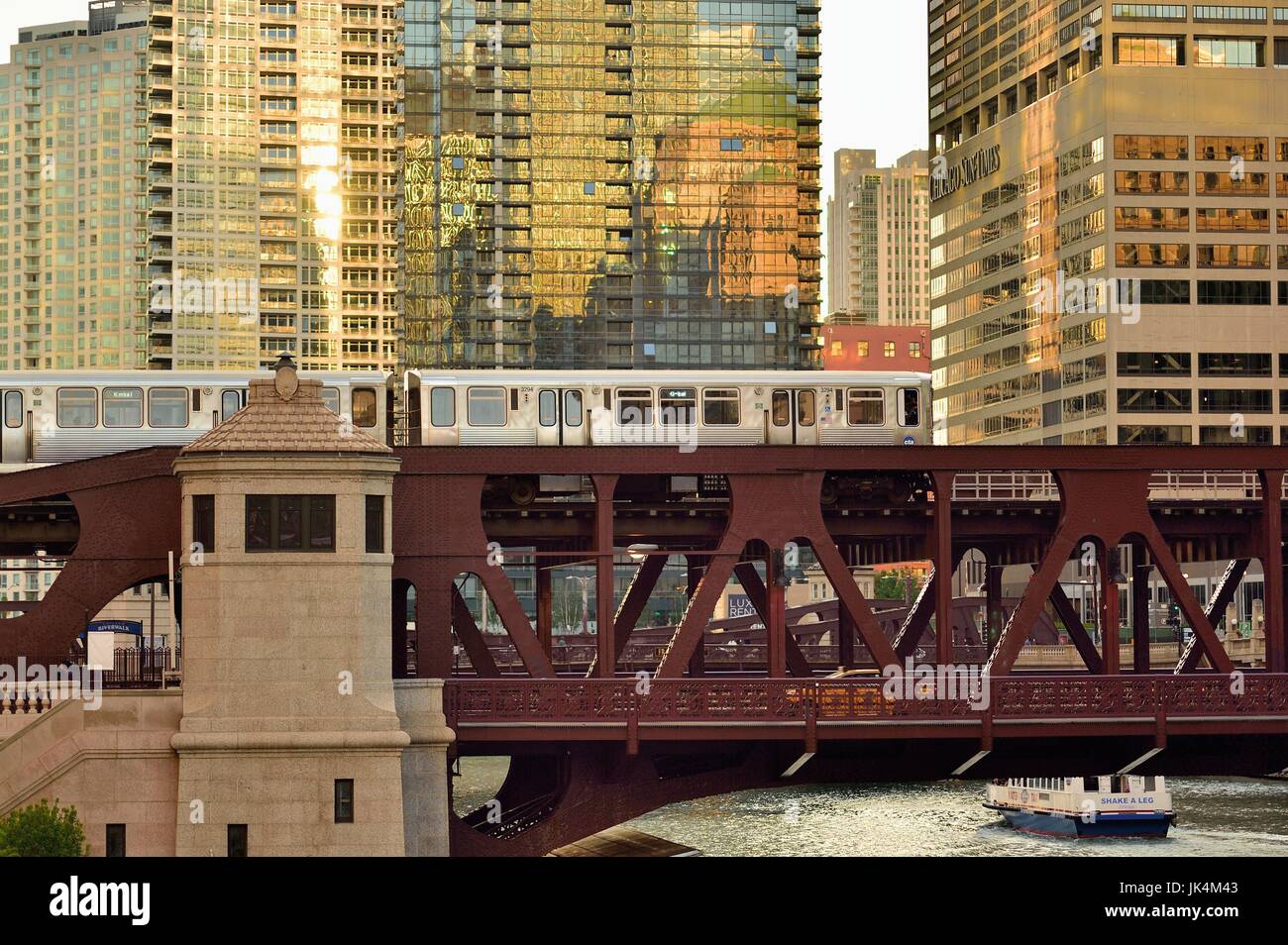 Die untergehende Sonne erzeugt Reflexionen aus einer Vielzahl von Gebäuden als CTA-Bahn überquert den Chicago River. Chicago, Illinois, USA. Stockfoto