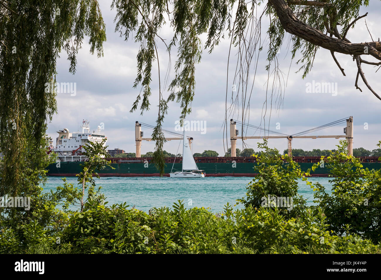 Detroit, Michigan - ein Segelboot geht Bluewing, ein Great Lake-Massen-Frachter über den Detroit River. Stockfoto