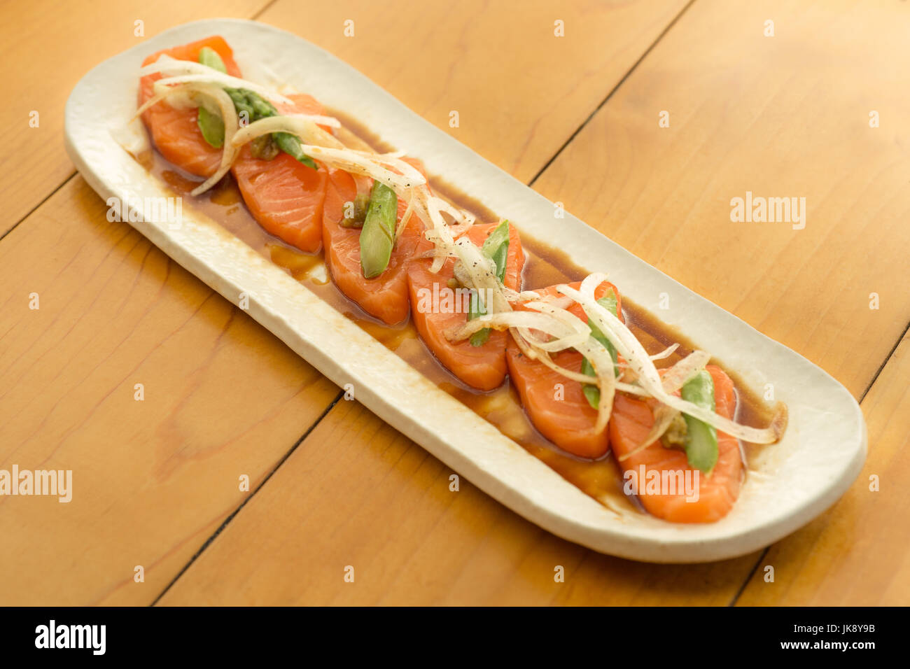 Lachs-Sashimi mit Spargel und Zwiebel auf Teller, bereit um zu essen. Stockfoto