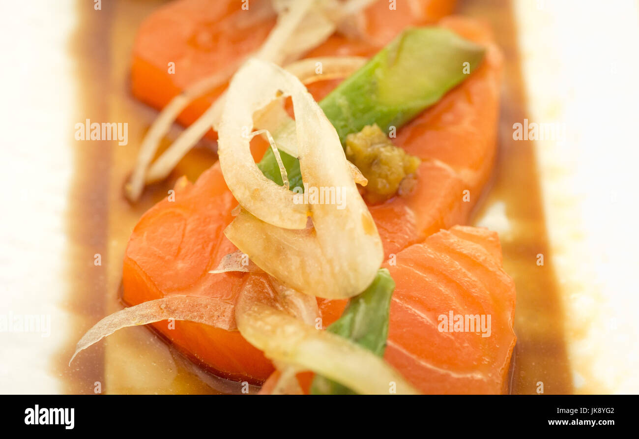 Lachs-Sashimi mit Spargel und Zwiebel auf Teller, bereit um zu essen. Stockfoto