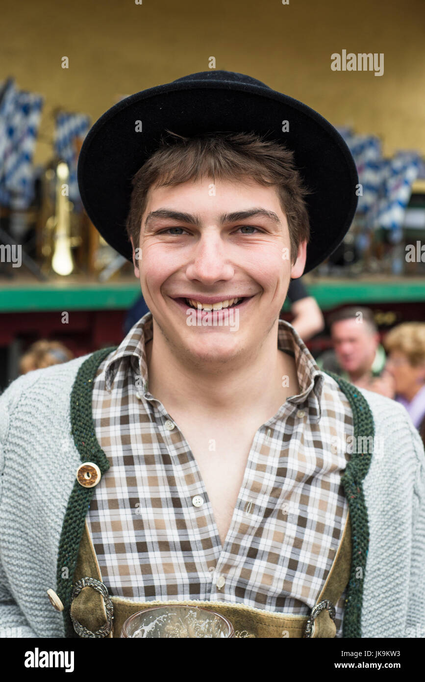 Porträt eines lächelnden jungen bayerischen Mannes in bayrischer Tracht mit Lederhosen, Filz schwarz, Hut, graue Strickjacke, braun kariertes Hemd Stockfoto