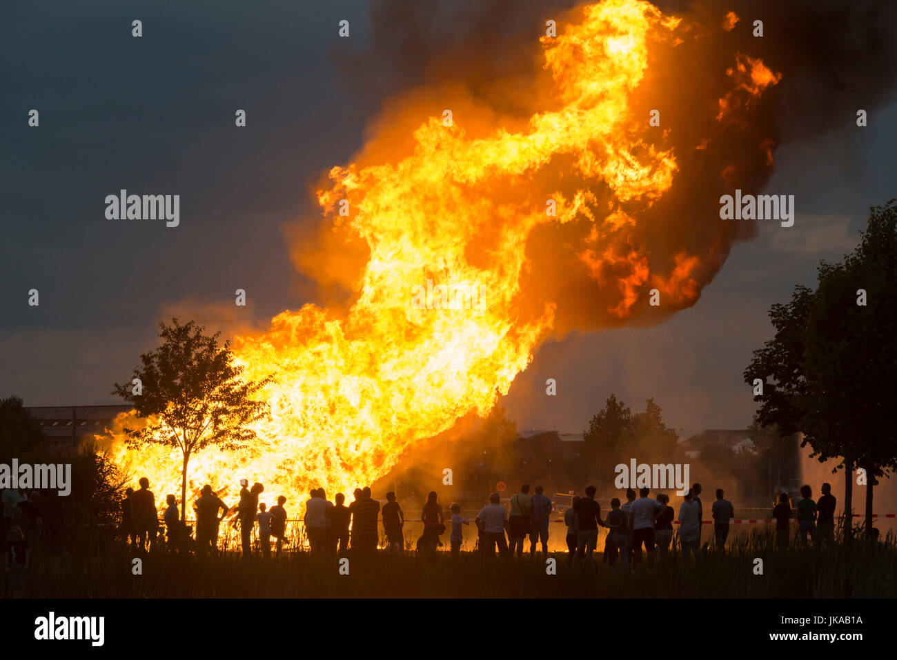 Silhouetten von Menschen vor den großen Flammen der Spalte des Feuers eine Sonnenwende feiern und Sonnwendfeuer Stockfoto