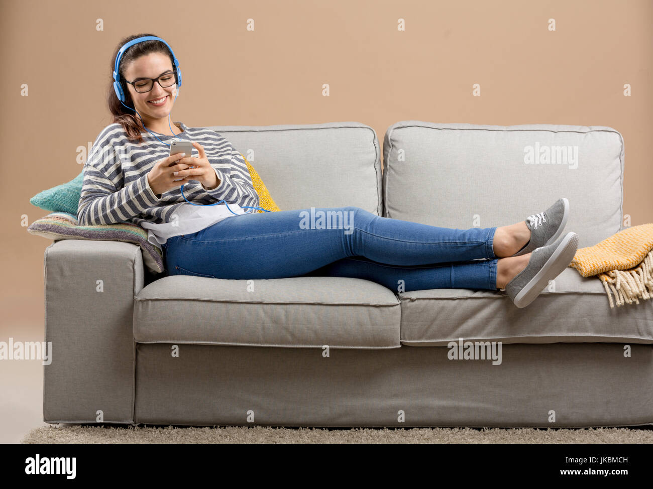 Schöne Frau zu Hause auf dem Sofa sitzen und Musik hören Stockfoto