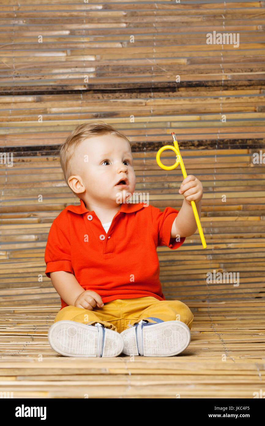 Baby Junge auf dem Boden sitzend Bambus Hintergrund einen Bleistift festhalten Stockfoto