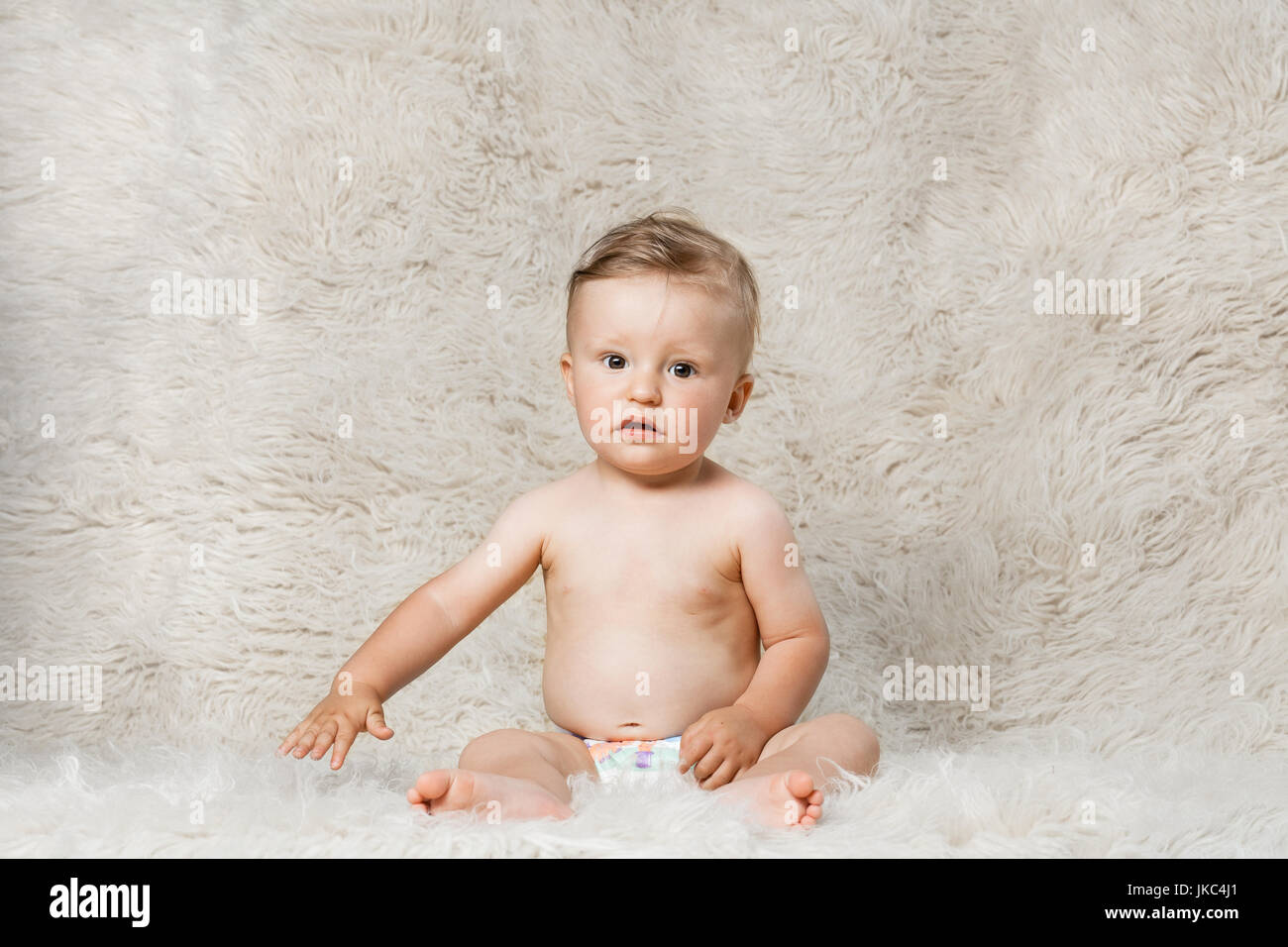 Baby Junge in Windeln, sitzen auf eine zottige hausgemachte Wolldecke Stockfoto