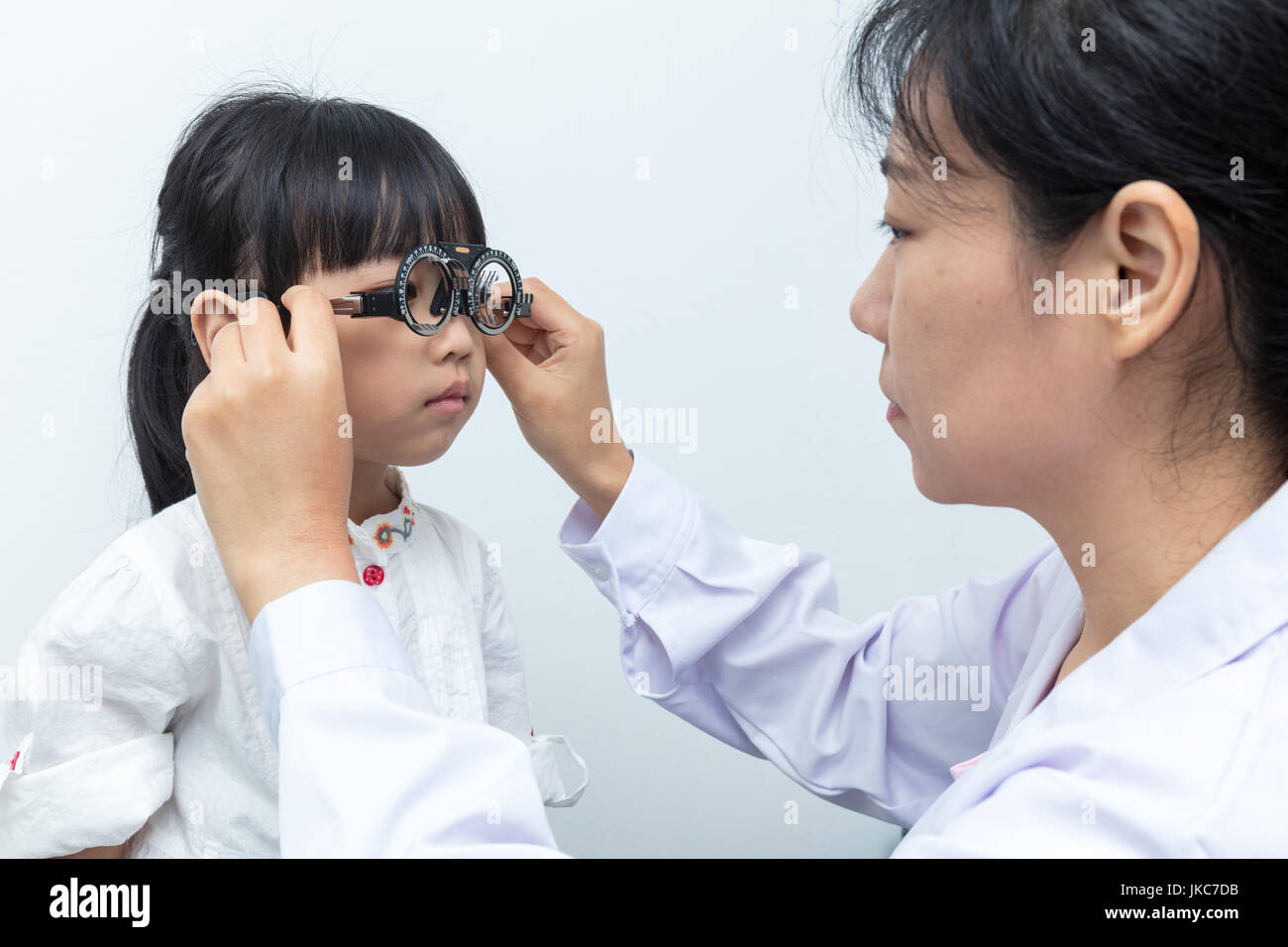 Asiatische kleine chinesische Mädchen tun Augen Prüfung durch Augenarzt in isolierten weißen Hintergrund Stockfoto