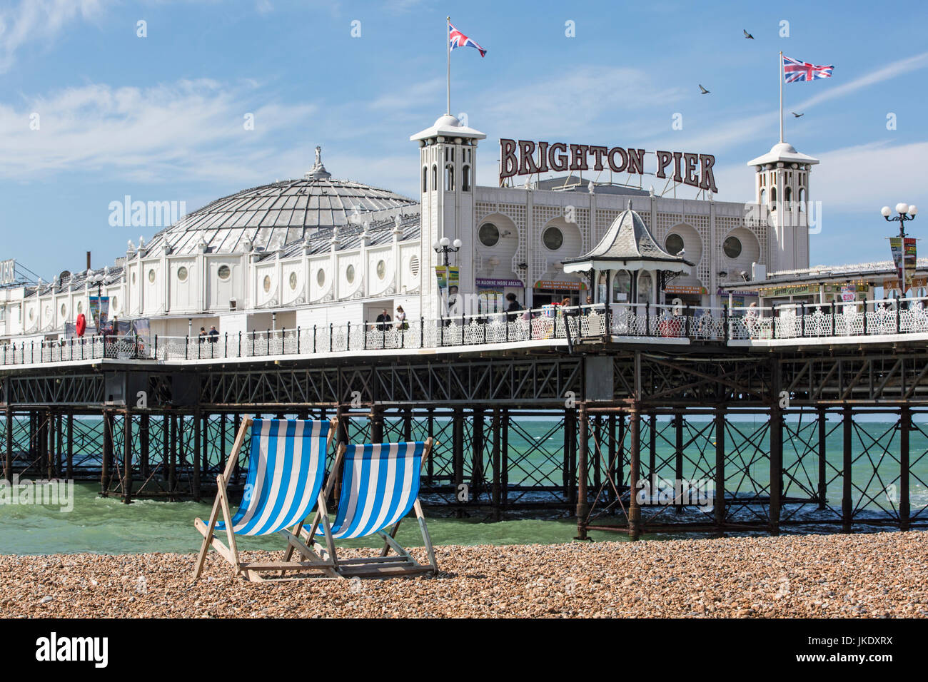 Zwei leere Liegestühle mit Blick auf Pier von Brighton an der Südküste von England. Stockfoto