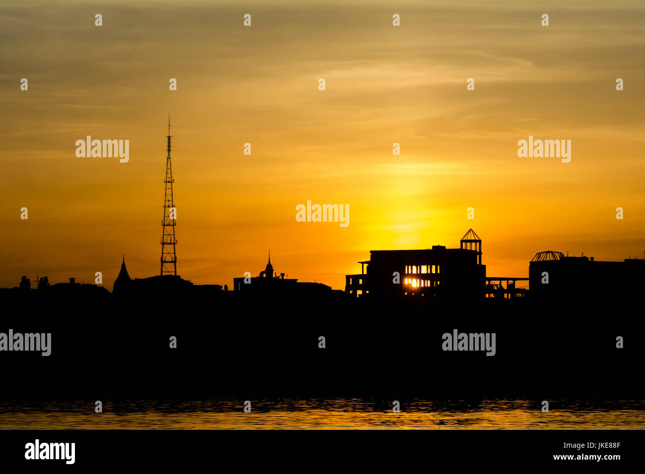 Dramatischen Sonnenuntergang über der Stadtsilhouette in der Nähe von Wasser Stockfoto