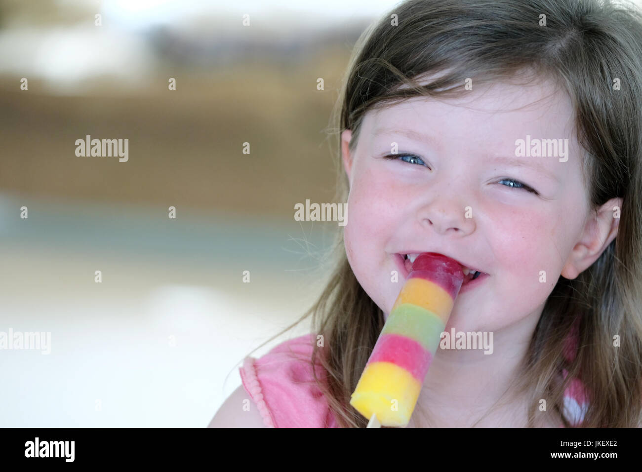 Ein kleines Kind eine bunte Eis am Stiel genießen. aufgenommen im Innenbereich in natürlichem Licht Stockfoto