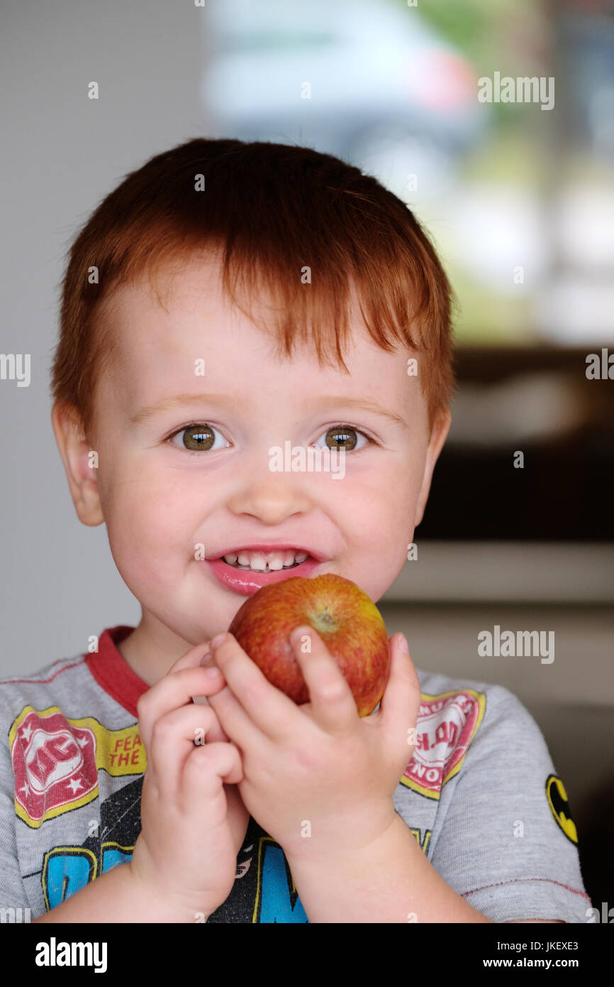 Eine junge, männliche Kind genießen Sie einen frischen, gesunden, Apfel. aufgenommen in der Heimat mit natürlichem Licht Stockfoto