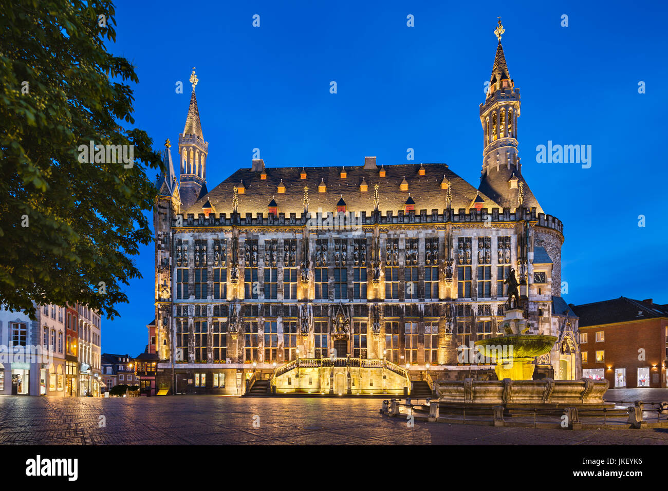 Das berühmte alte Rathaus von Aachen, Deutschland mit blauen Nachthimmel gesehen vom Marktplatz mit dem Karls-Brunnen auf der rechten Seite. Genommen mit einem Shift-l Stockfoto