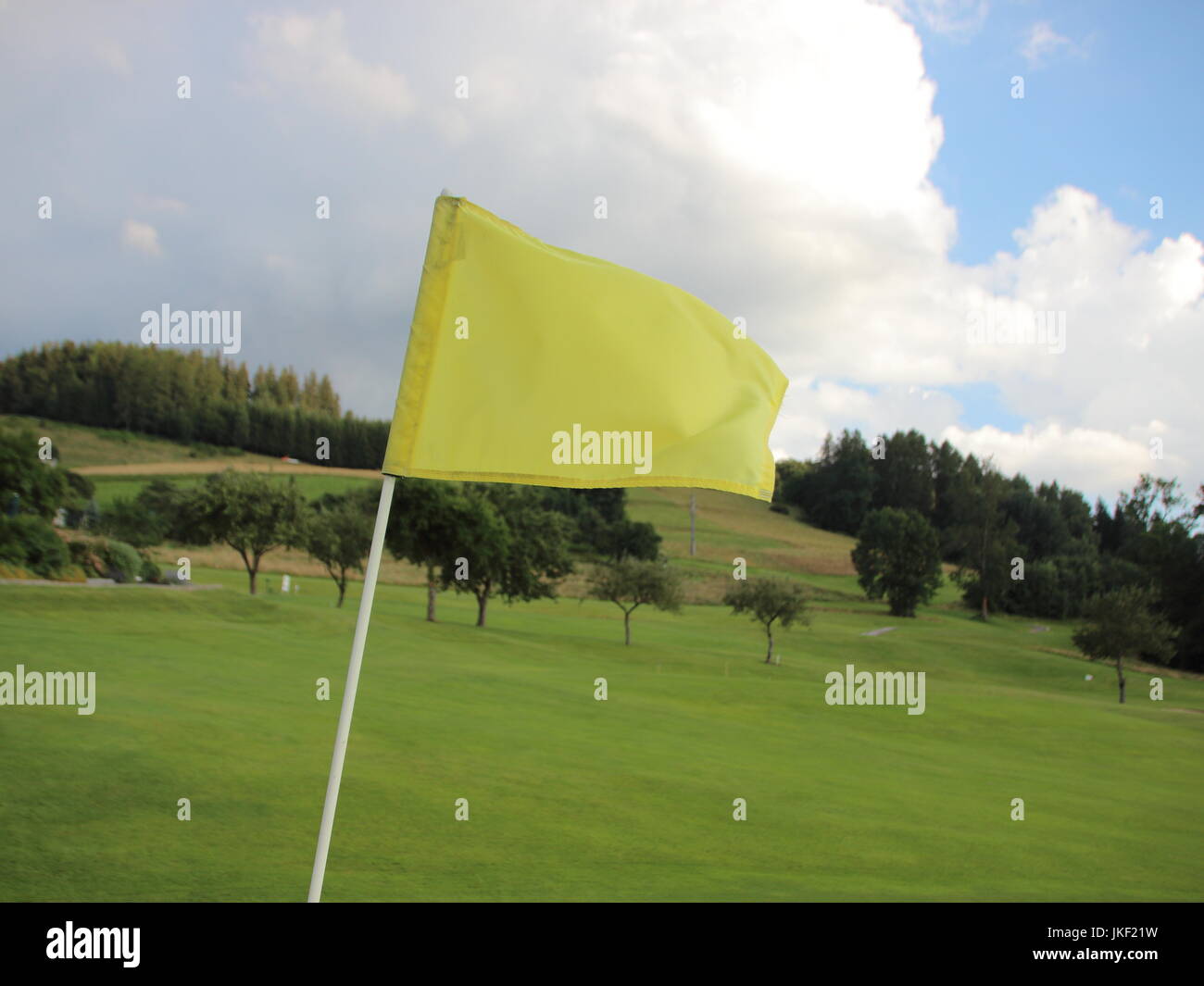 Gelbe windigen Flagge am Golfplatz mit Gebirgshintergrund Stockfoto