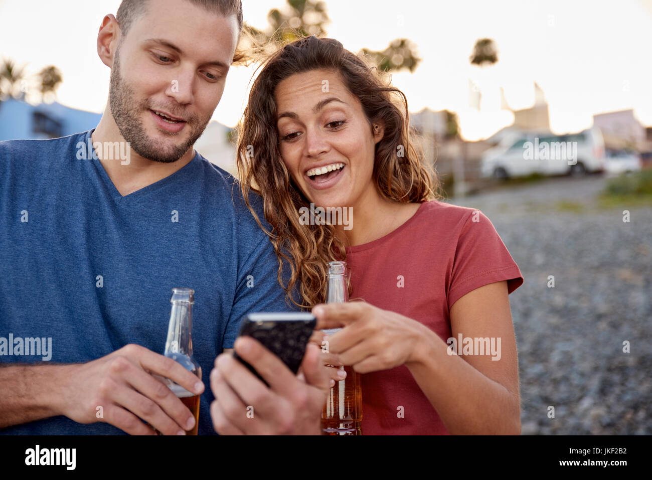 Paar mit Bierflaschen Zelle Telefon am Strand Stockfoto