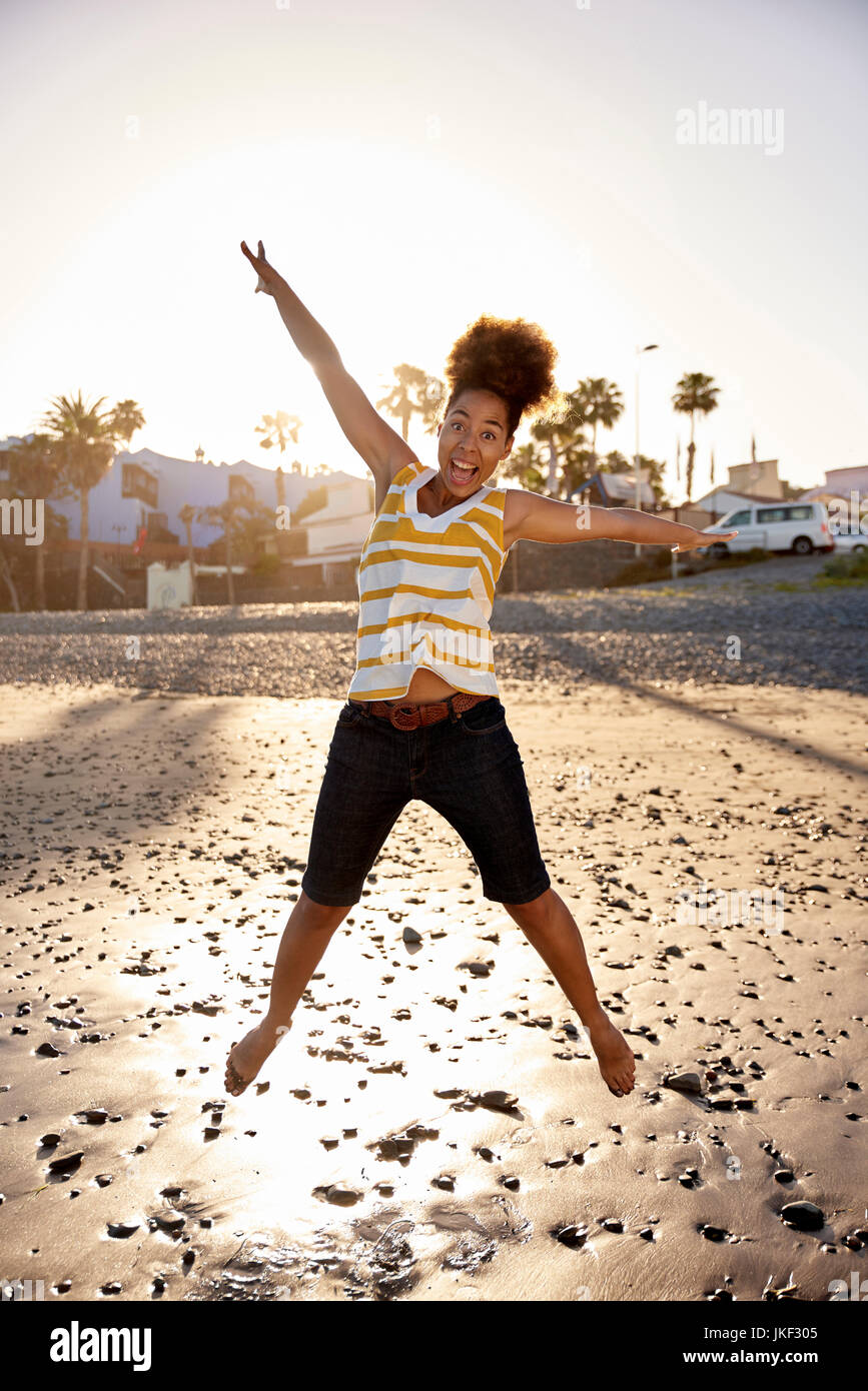 Glückliche Frau springen in die Luft am Strand Stockfoto