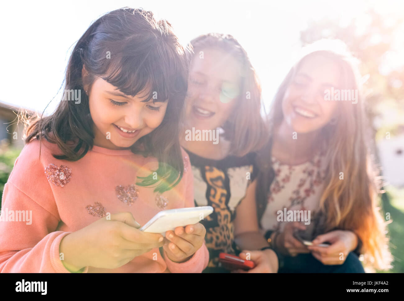 Drei glückliche Mädchen über ihre Smartphones im Freien Stockfoto