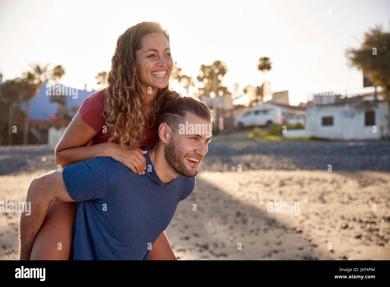 Junge Mann seiner Freundin ein huckepack Fahrt am Strand geben Stockfoto