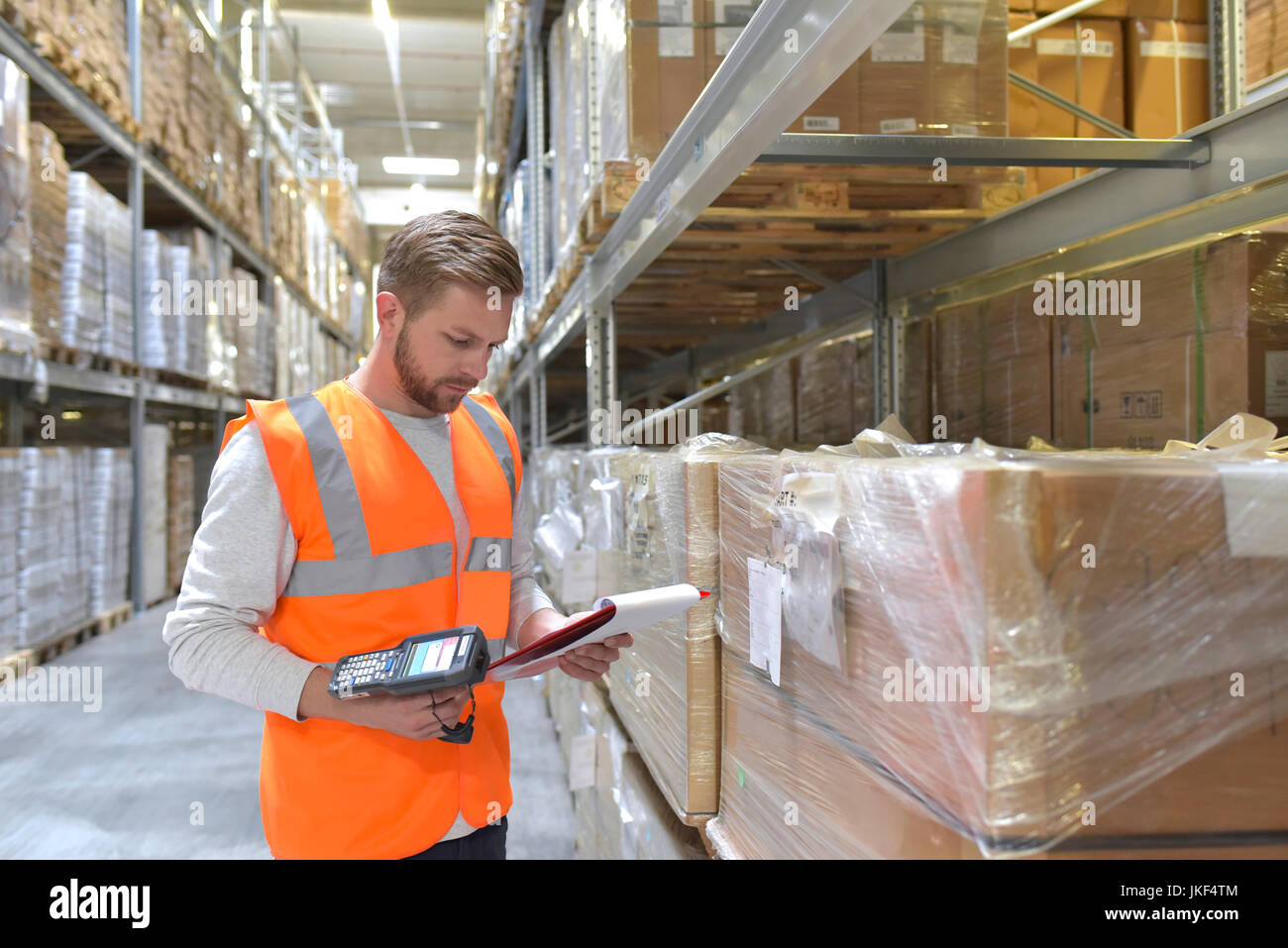 Mann in Halle das Tragen von Warnwesten holding Zwischenablage und Barcode Scanner Stockfoto