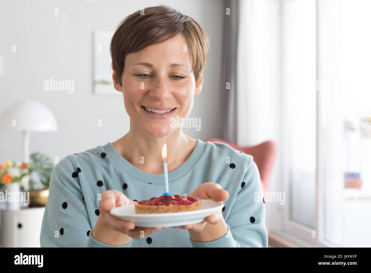 Porträt der lächelnde Frau Halteplatte mit Geburtstagstorte Stockfoto