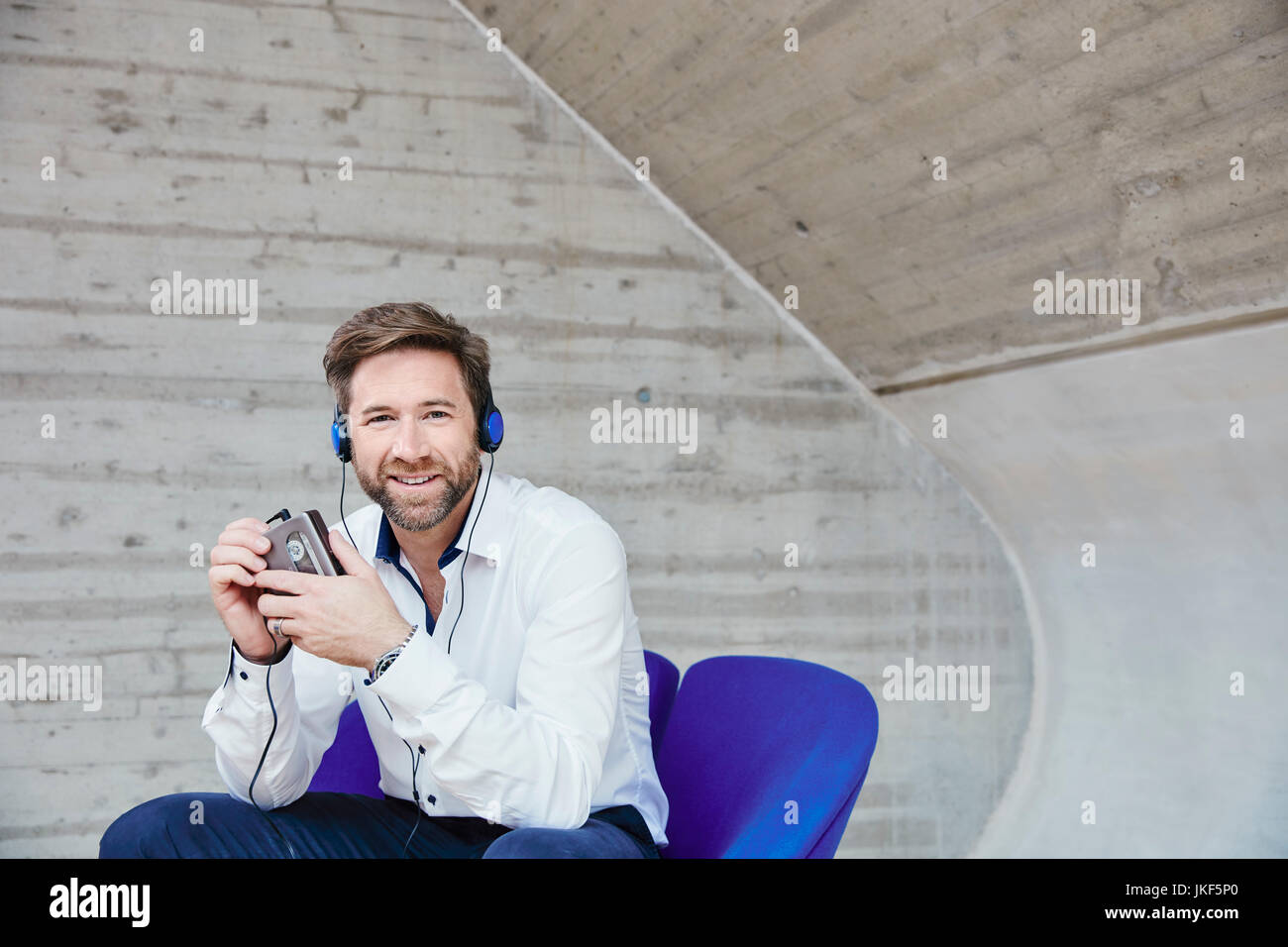 Mann sitzt auf Stuhl Musikhören von Walkman® Stockfoto