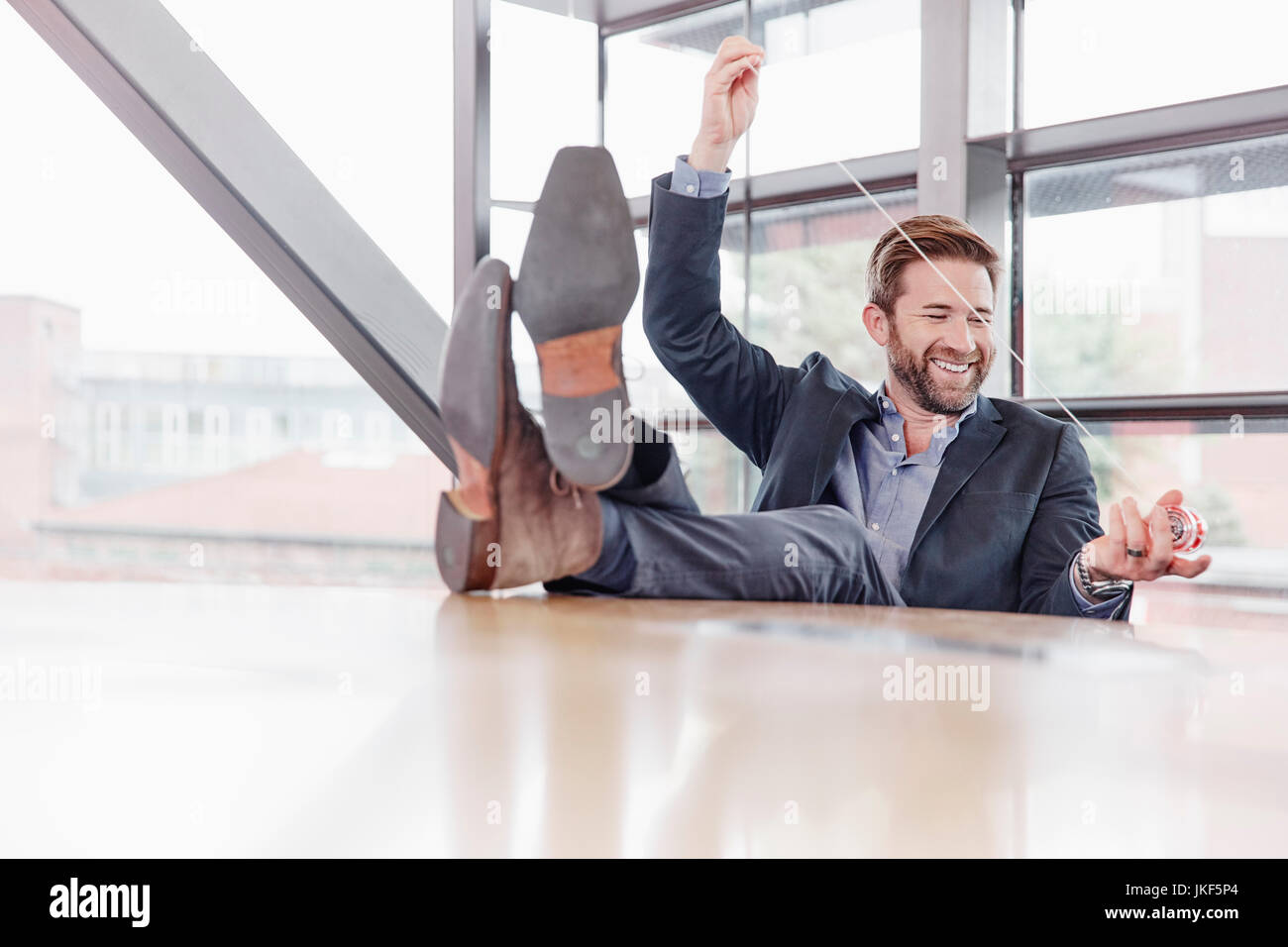 Happy Geschäftsmann seine Füße auf den Tisch spielen Mit yoyo Stockfoto