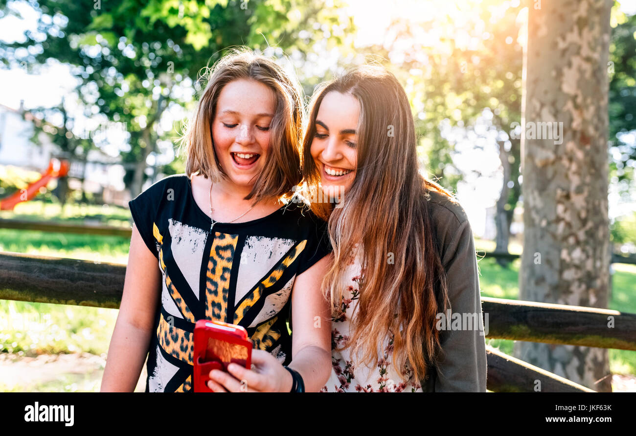 Zwei Mädchen Spaß mit Ihrem Smartphone im Freien Stockfoto