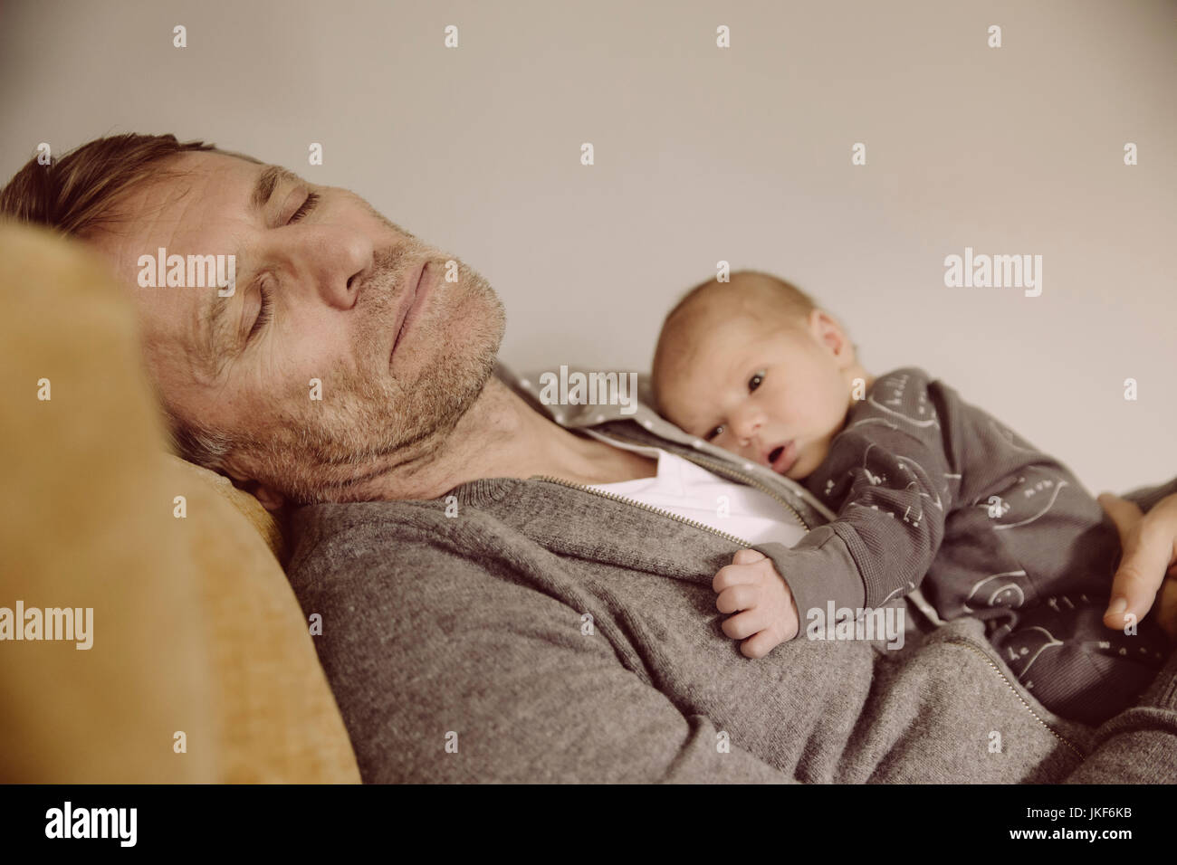 Vater ein Nickerchen mit Neugeborenen wach auf seiner Brust Stockfoto