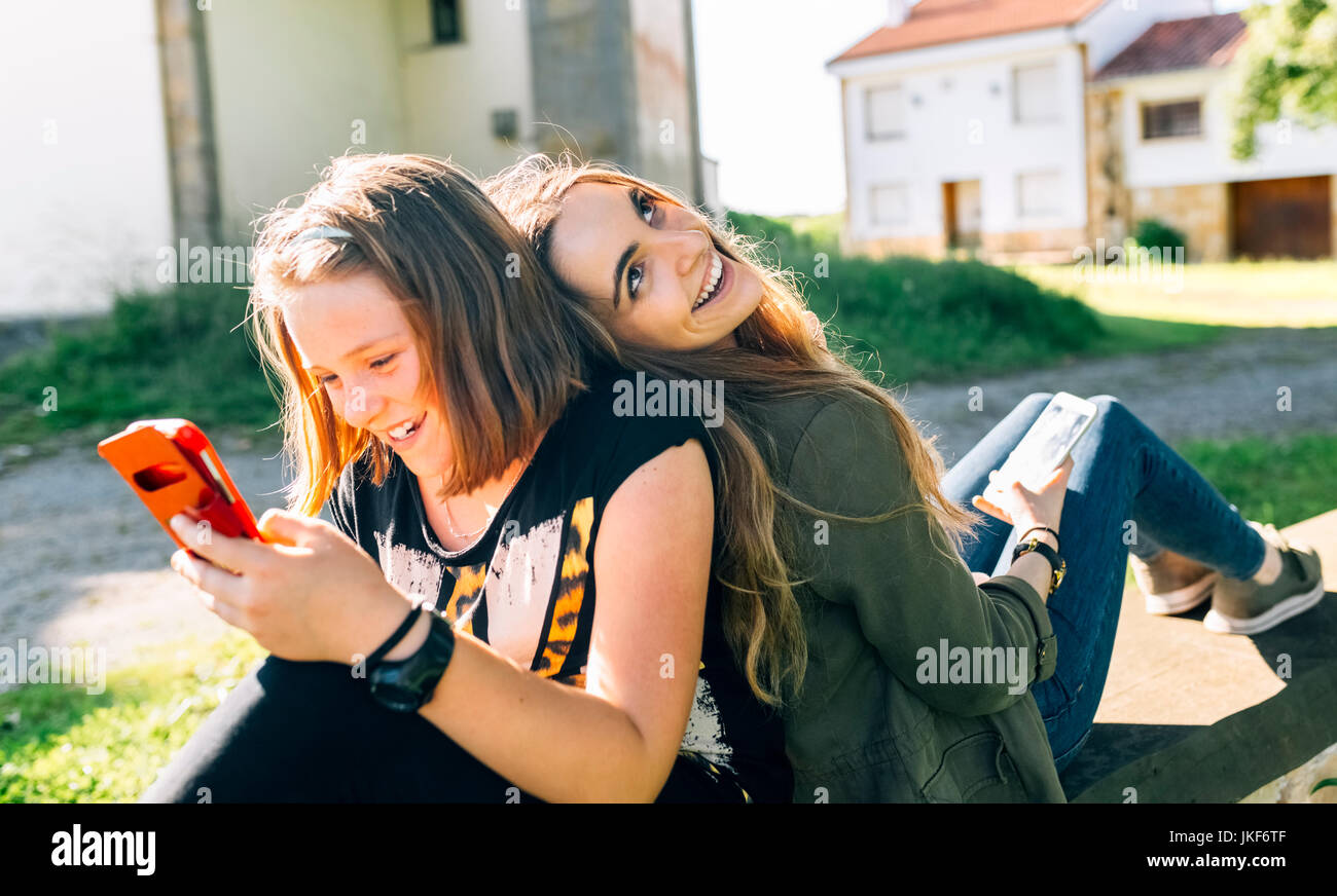Zwei glückliche Mädchen über ihre Smartphones im Freien Stockfoto