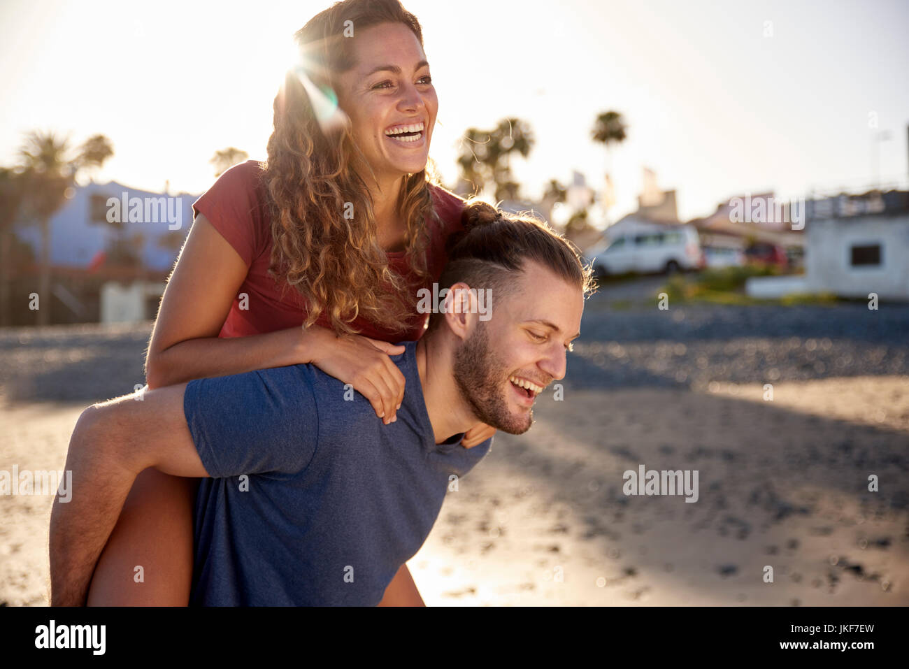 Junge Mann seiner Freundin ein huckepack Fahrt am Strand geben Stockfoto