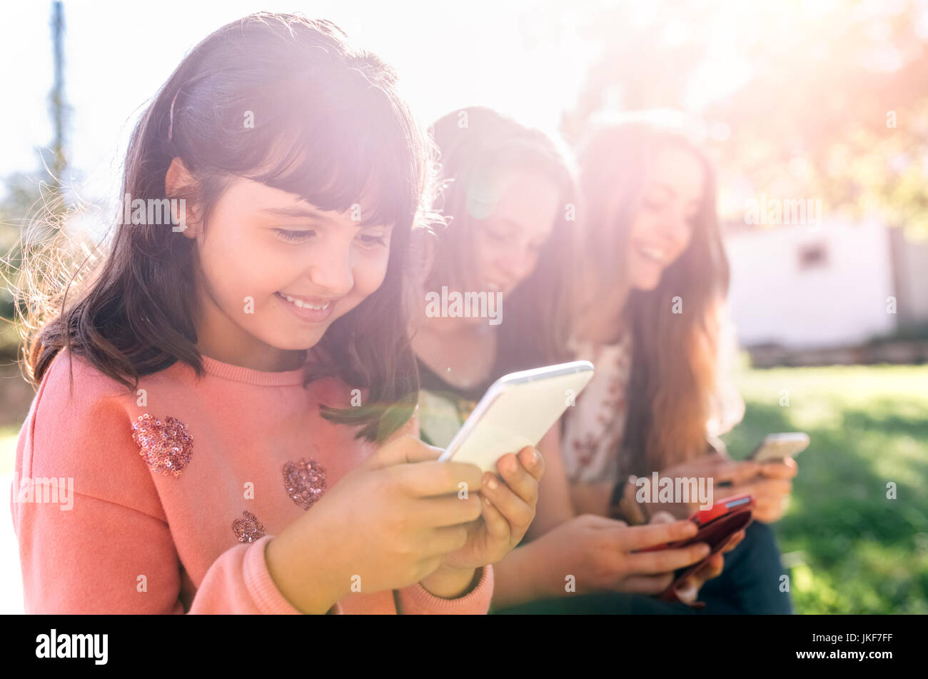 Drei glückliche Mädchen über ihre Smartphones im Freien Stockfoto