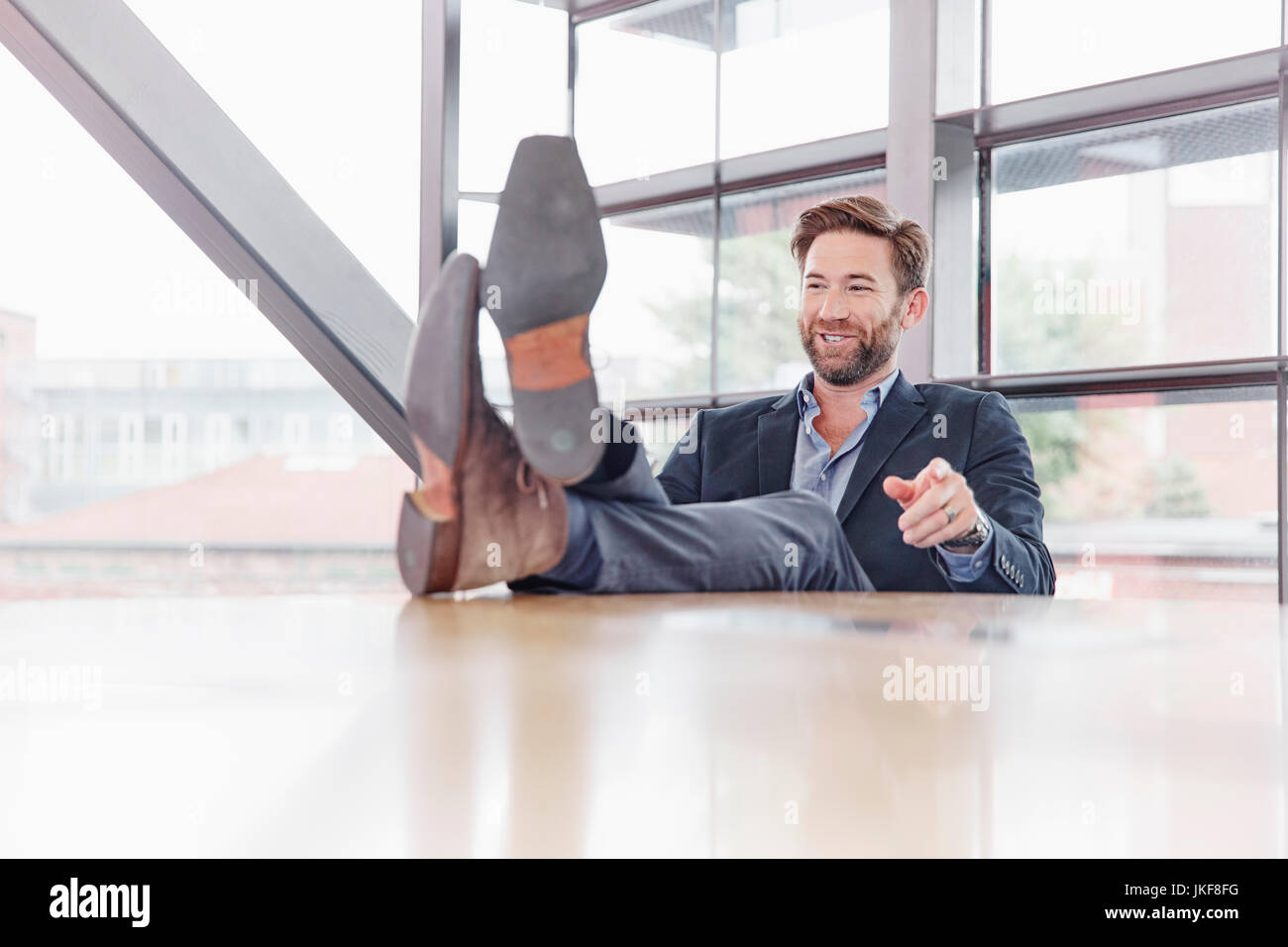 Lächelnd Geschäftsmann seine Füße auf den Tisch Stockfoto