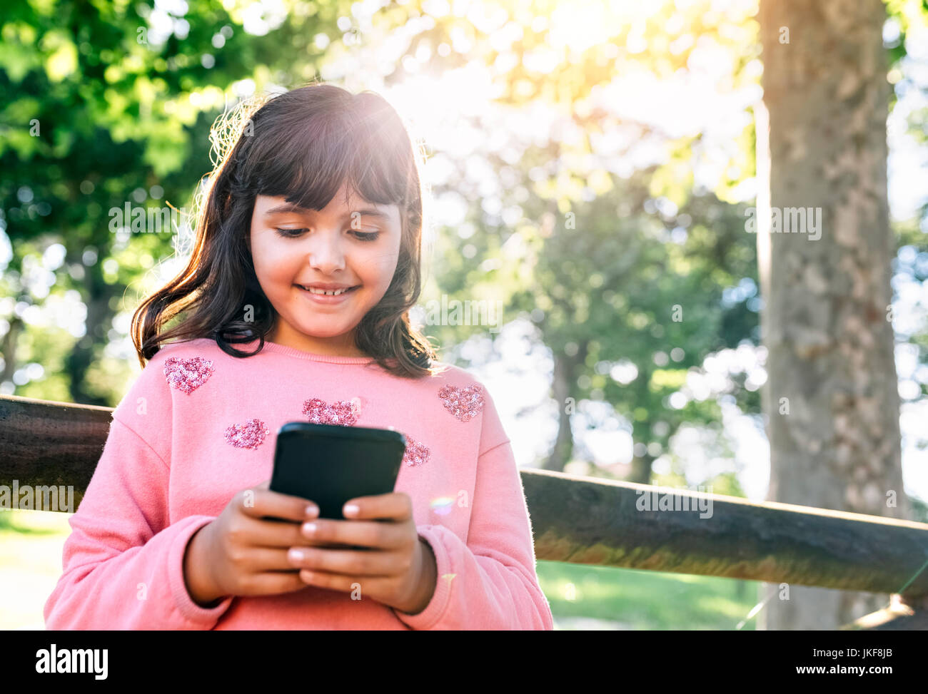 Lächelnde Mädchen Senden von Nachrichten mit Ihrem Smartphone Stockfoto